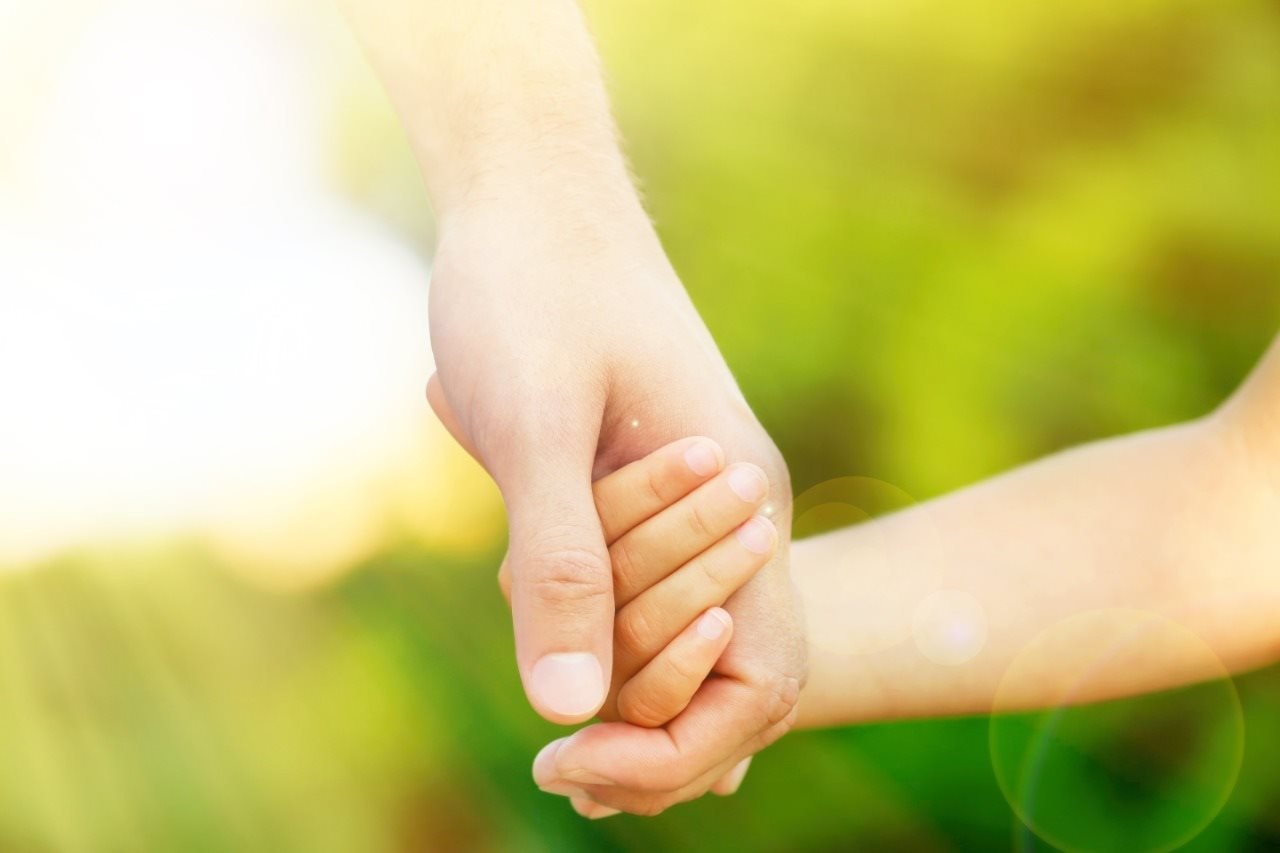 Fotografía de la mano de un adulto tomando la mano de un infante